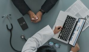 overhead shot of physician explaining insurance options to a male patient on a laptop